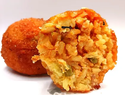 Arancino Ragù tagliato a metà, ripieno rosso con pomodoro e piselli