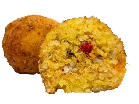 Arancino Baccalà e Peperoni tagliato a metà, riso allo zafferano con baccalà e peperone rosso, accanto a un arancino intero
